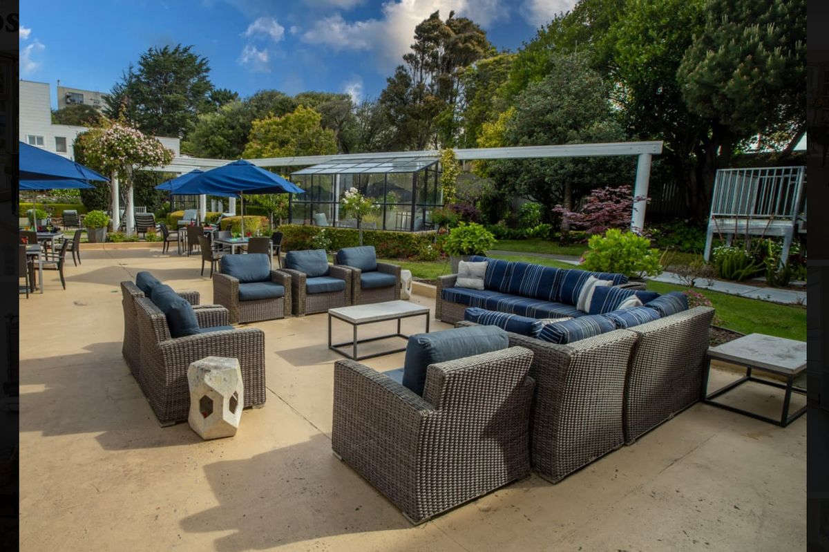 A spacious outdoor patio with comfortable seating arrangements surrounded by lush greenery.