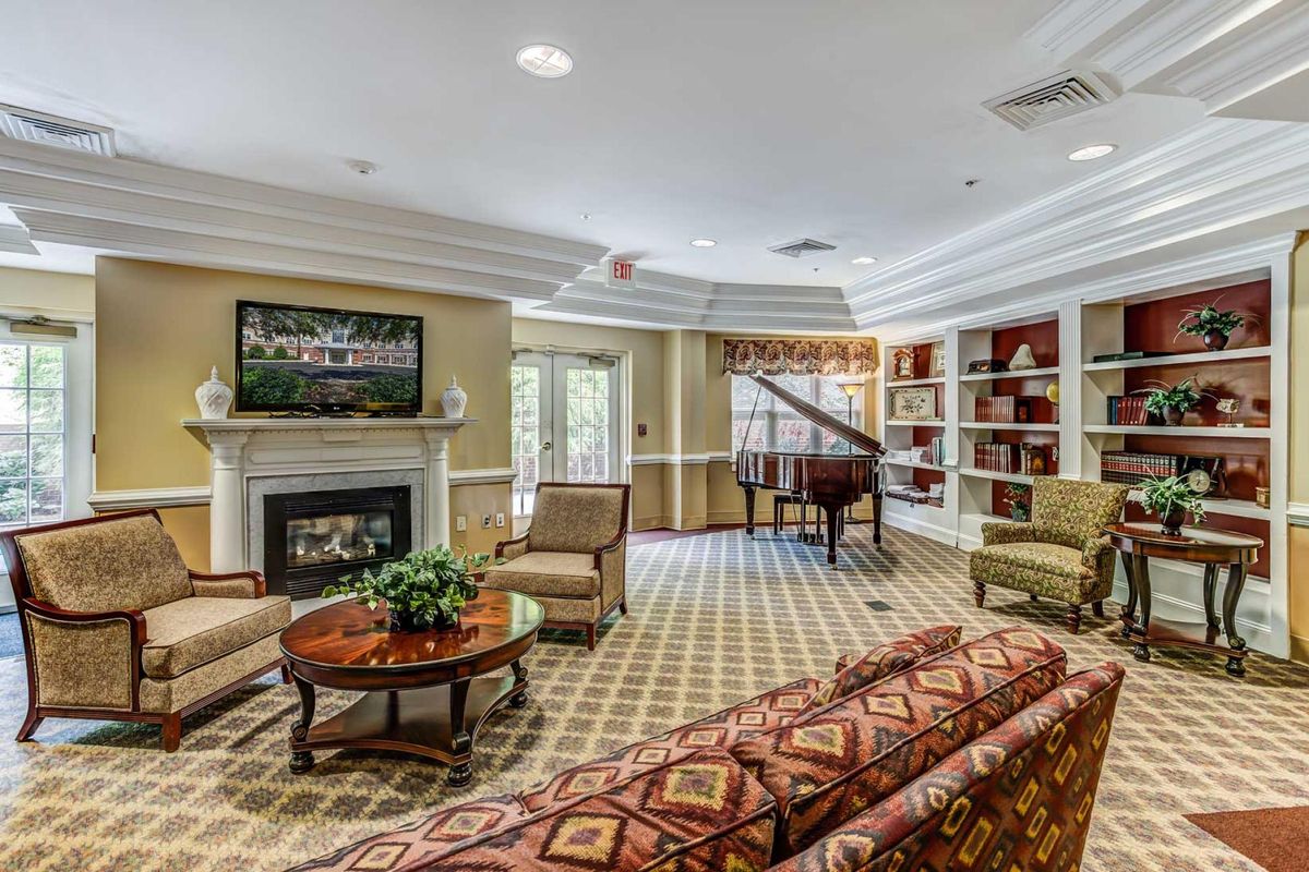 A cozy living room with a grand piano, fireplace, and comfortable seating.