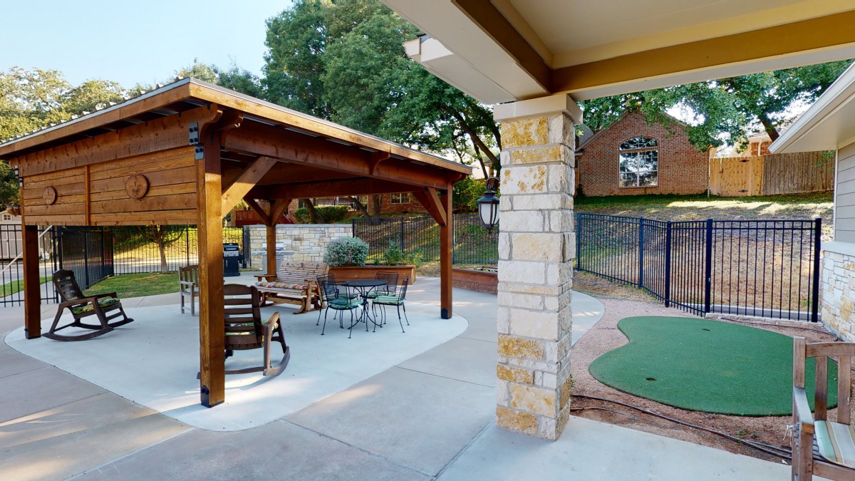 A cozy backyard with a wooden gazebo, outdoor seating, and landscaped surroundings.