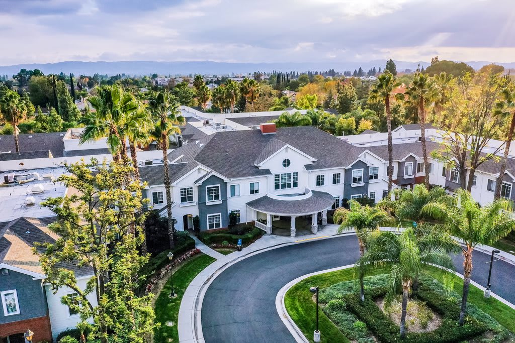 Aerial view of a large house with a circular driveway surrounded by trees.