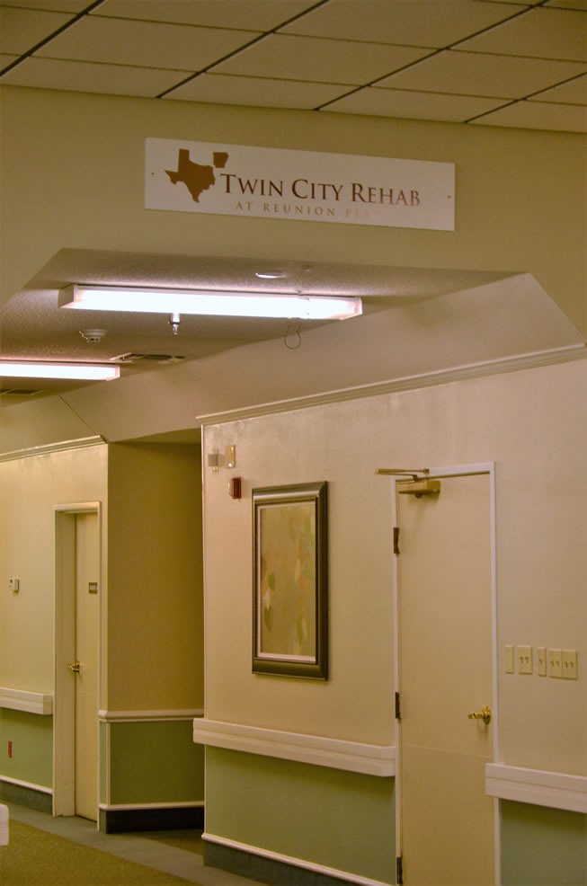 A hallway interior with a Twin City Rehab sign above the door.