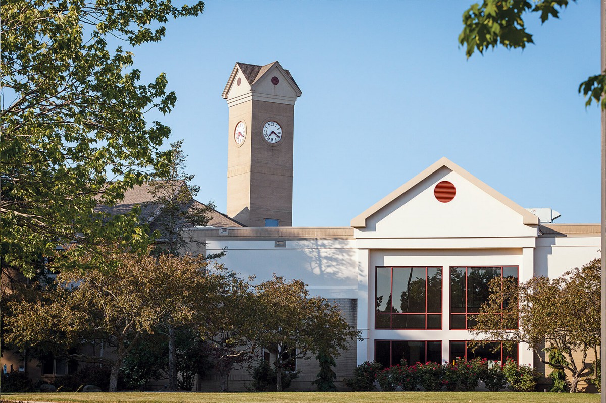 A building with a clock tower surrounded by trees under a clear blue sky.