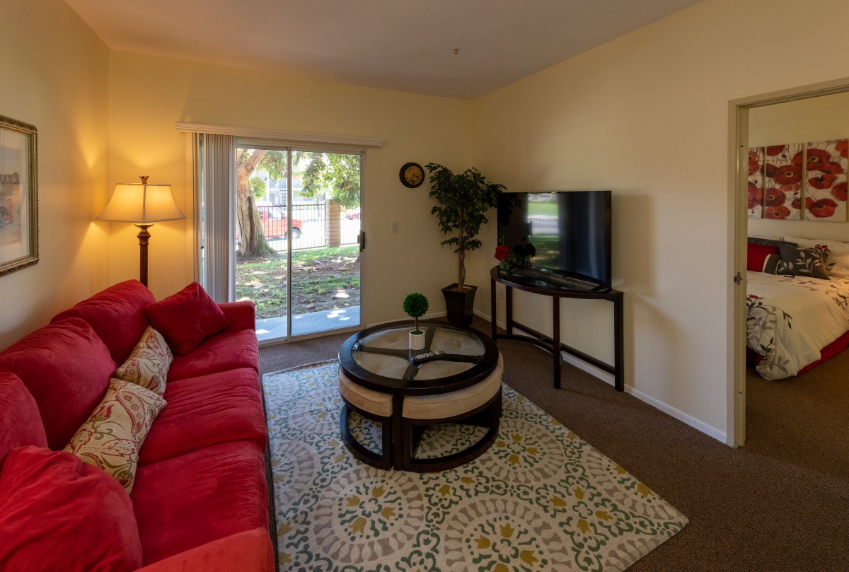 A cozy living room with a red sofa and a modern coffee table facing a television, featuring warm lighting and decor.