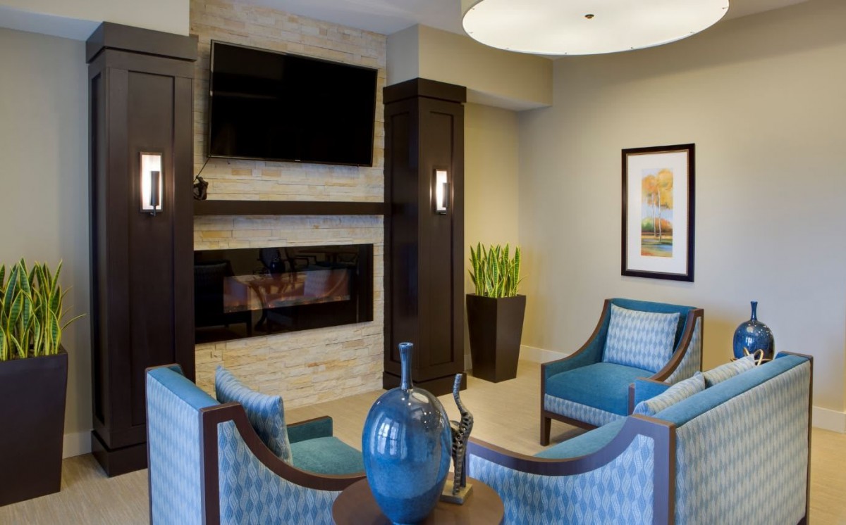 A modern living room with a fireplace, TV, and blue seating.