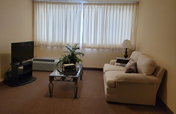 A cozy living room with a sofa, coffee table, and television.