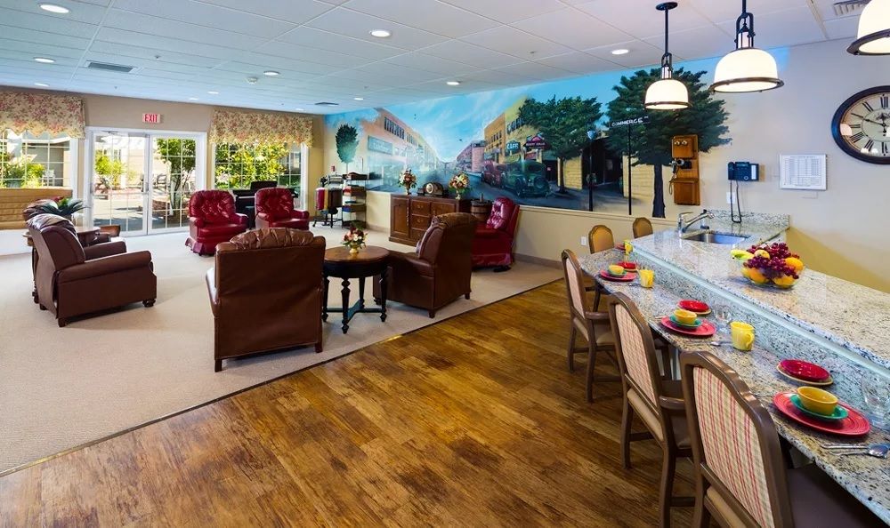 A cozy living area with armchairs and a mural, adjacent to a kitchen counter with seating.