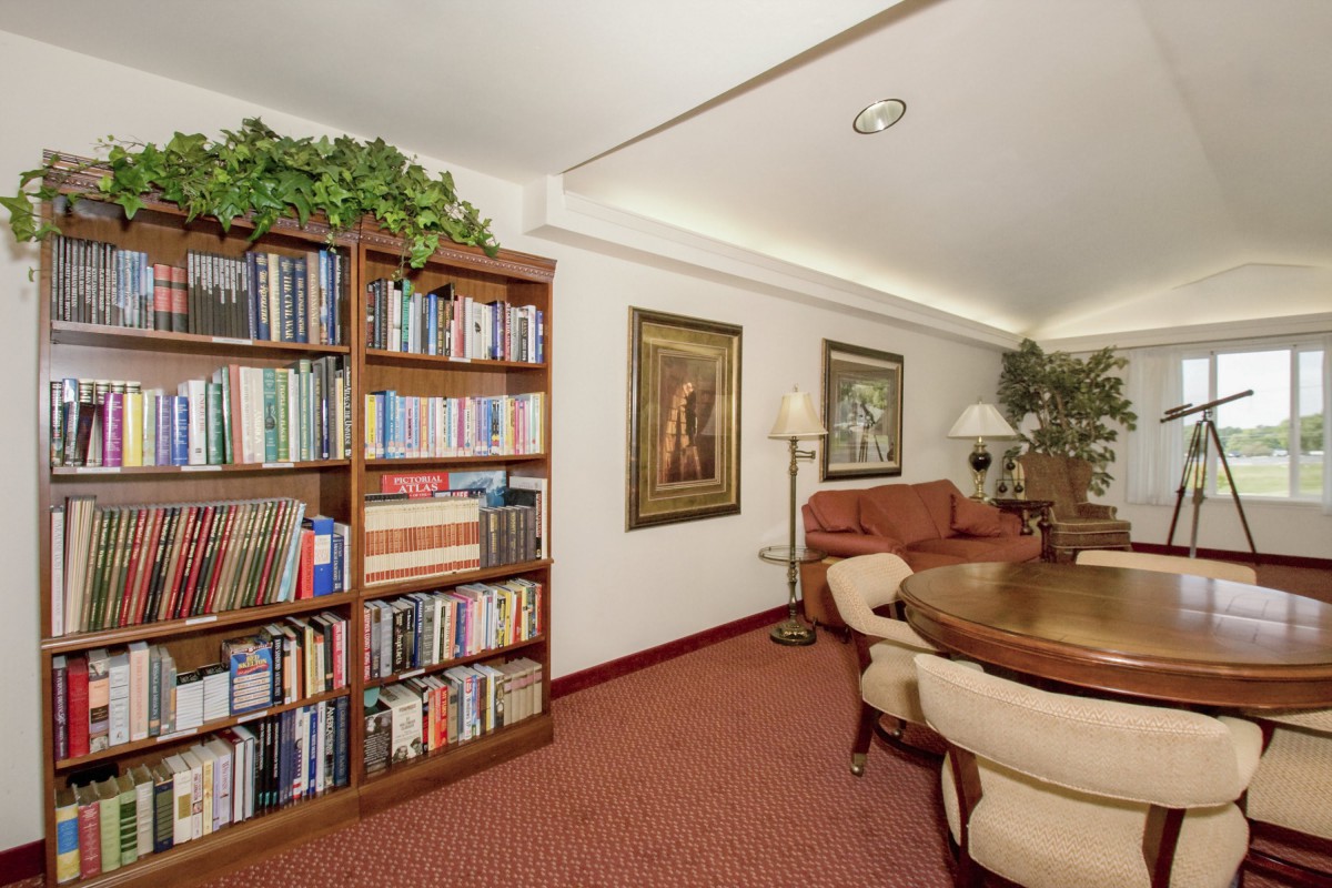 A cozy living room with a well-stocked bookshelf, comfortable seating, and decorative artwork.