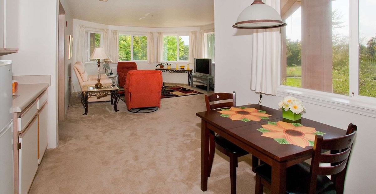 A cozy living room with red chairs and natural light streaming through large windows.