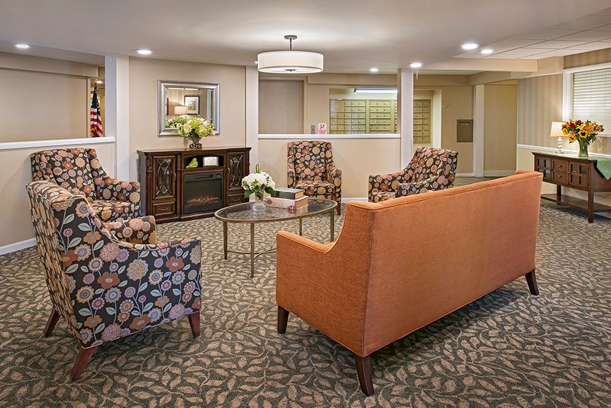 A cozy living room with patterned chairs, an orange sofa, and a coffee table.