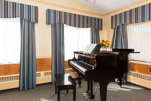A beautifully arranged music room featuring a grand black piano and elegant striped curtains.