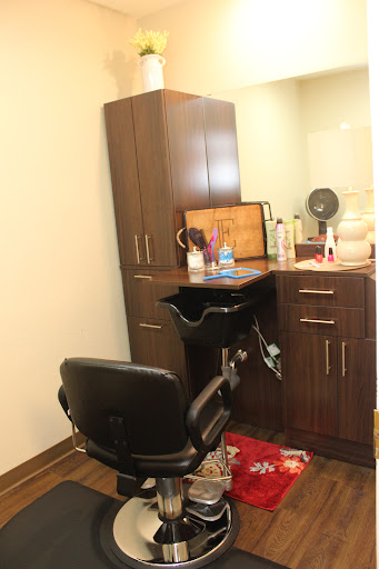 A view of a hair salon setup featuring a styling chair, wooden cabinetry, and various cosmetic products.