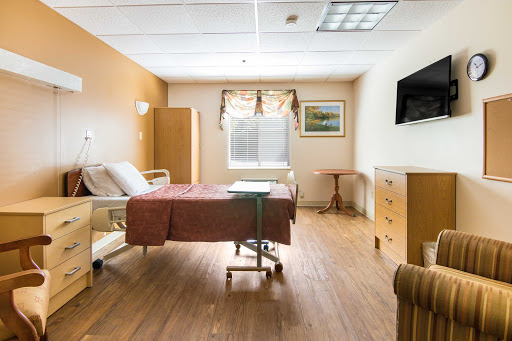 A clean and well-lit hospital patient room equipped with essential furniture.