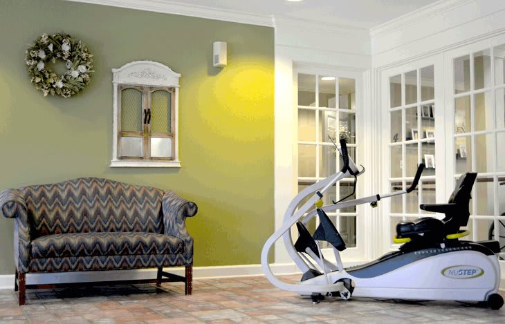 A stylish home gym setup with an elliptical trainer and a comfortable sofa in the living area.