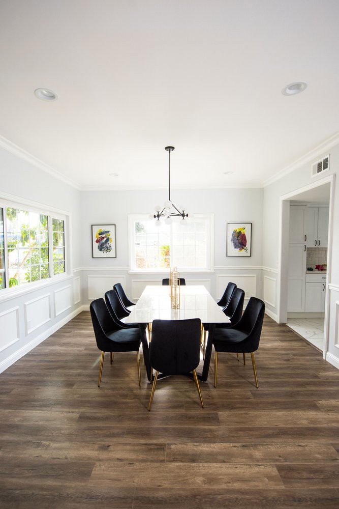 A modern dining room with a large table, black chairs, and elegant decor.