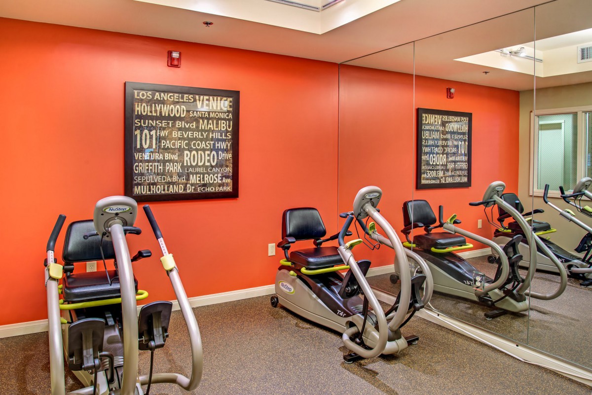 A gym room with cardio exercise machines and motivational wall art.