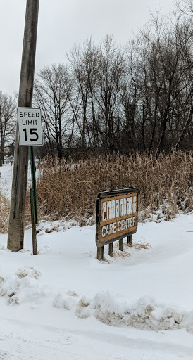 A snow-covered landscape featuring a speed limit sign of 15 mph and a wooden sign partially obscured by snow.