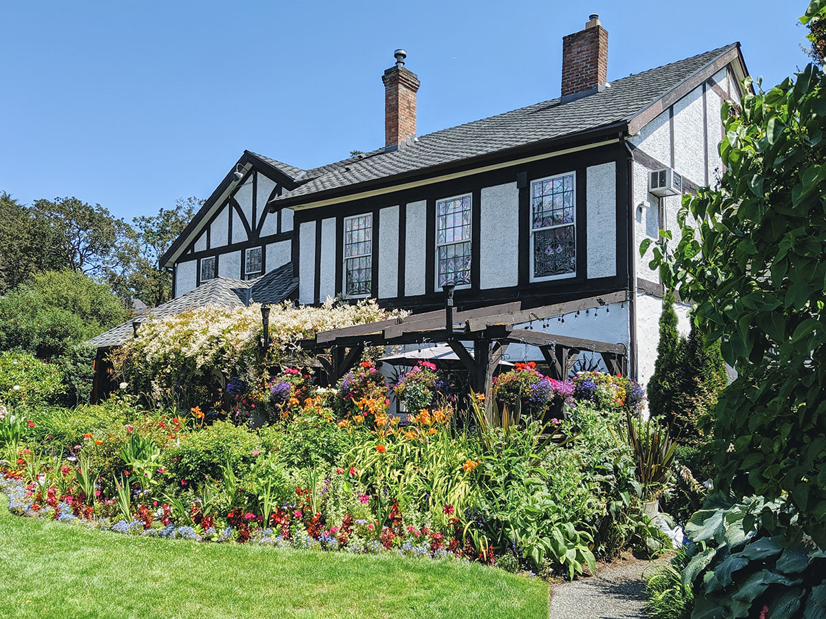 A charming Tudor-style house with a vibrant garden full of flowers.