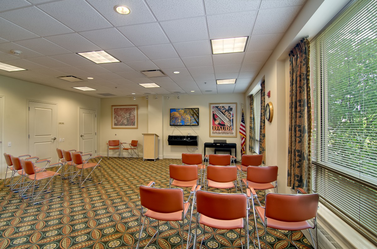 A conference room with rows of chairs facing a podium and artwork on the walls.