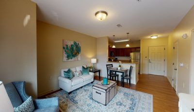 A cozy apartment living room with a sofa, dining set, and open kitchen area.