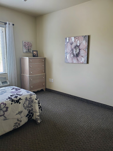 A cozy and simple bedroom featuring a tasteful dresser, decorative wall art, and inviting bedding.