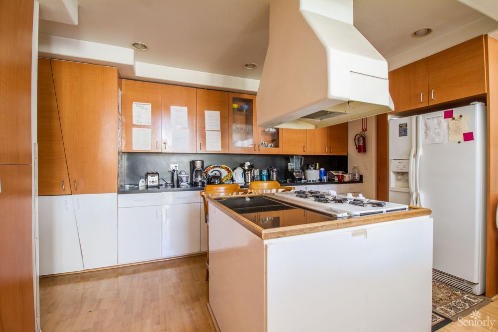 A modern kitchen with wooden cabinets and a central island featuring a stovetop.