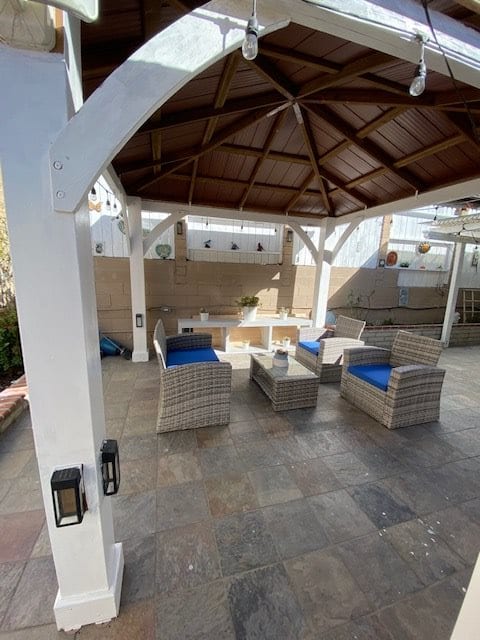 A cozy outdoor seating area with wicker furniture under a gazebo.