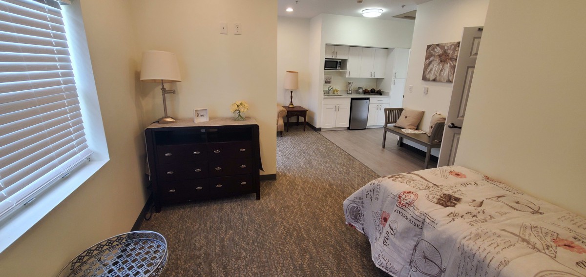 A cozy apartment interior featuring a bedroom and kitchenette.