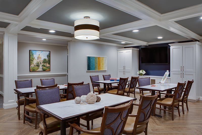 A modern dining room with neatly arranged tables and chairs, featuring elegant lighting and wall art.