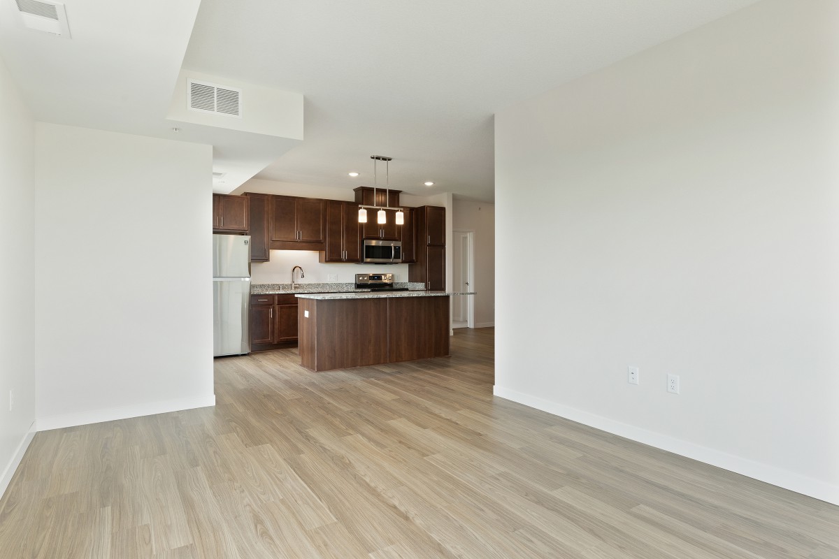 A modern open floor plan apartment with a spacious kitchen and wood flooring.