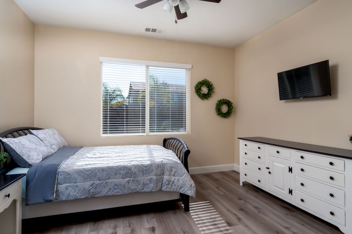 A modern bedroom with a bed, dresser, and wall-mounted TV.