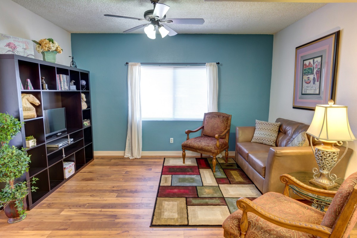 A cozy living room with a sofa, armchairs, and a colorful rug on hardwood flooring.