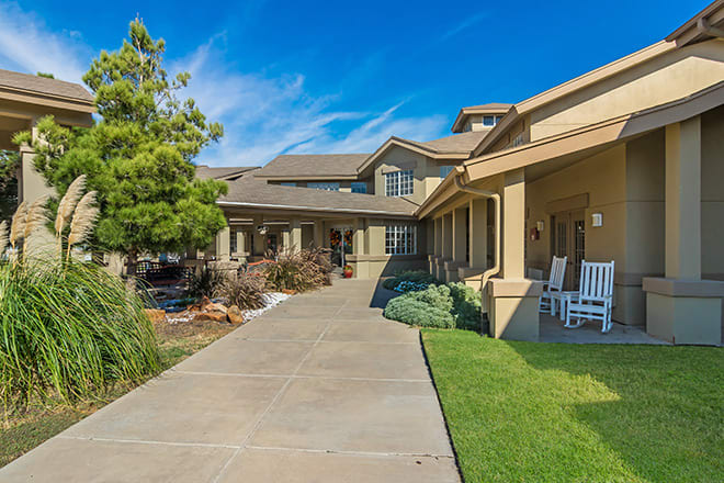 A spacious residential house with a large porch and landscaped front yard.