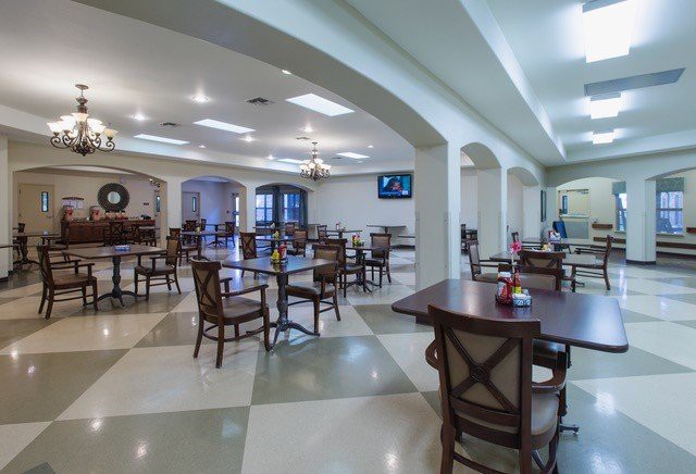 A modern dining area with neatly arranged tables and chairs, featuring elegant arches and soft lighting.