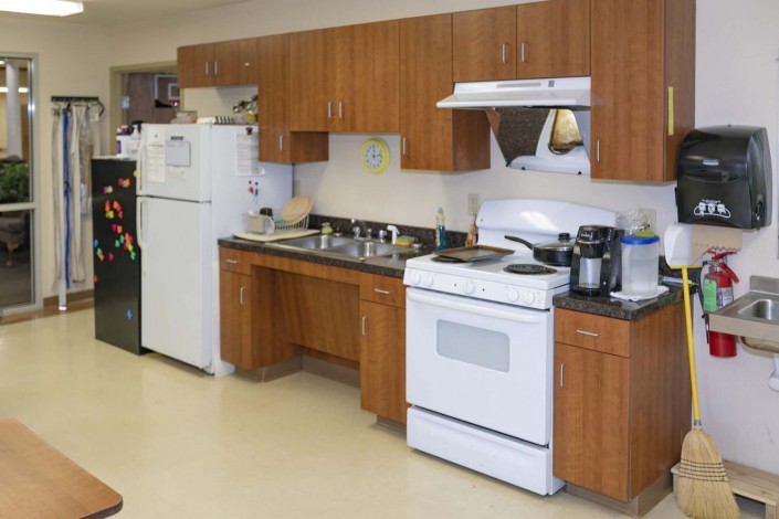 A kitchen with wooden cabinets, a refrigerator, stove, and sink.