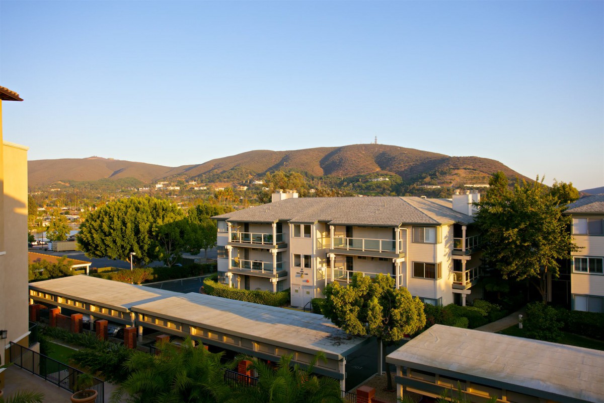 A scenic view of a residential building surrounded by lush greenery and hills in the background.