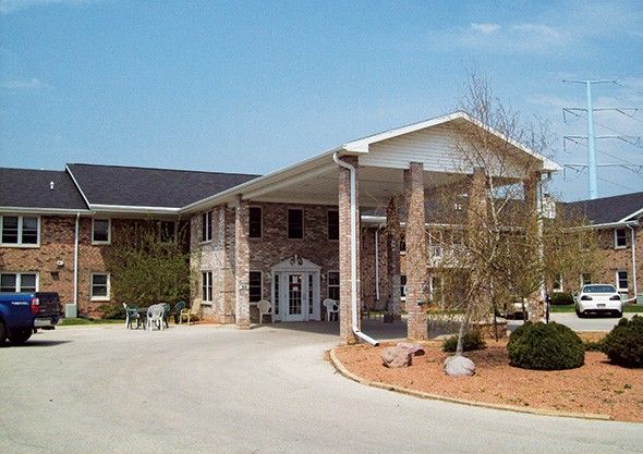 A two-story brick building with a covered entrance and surrounding landscaping.