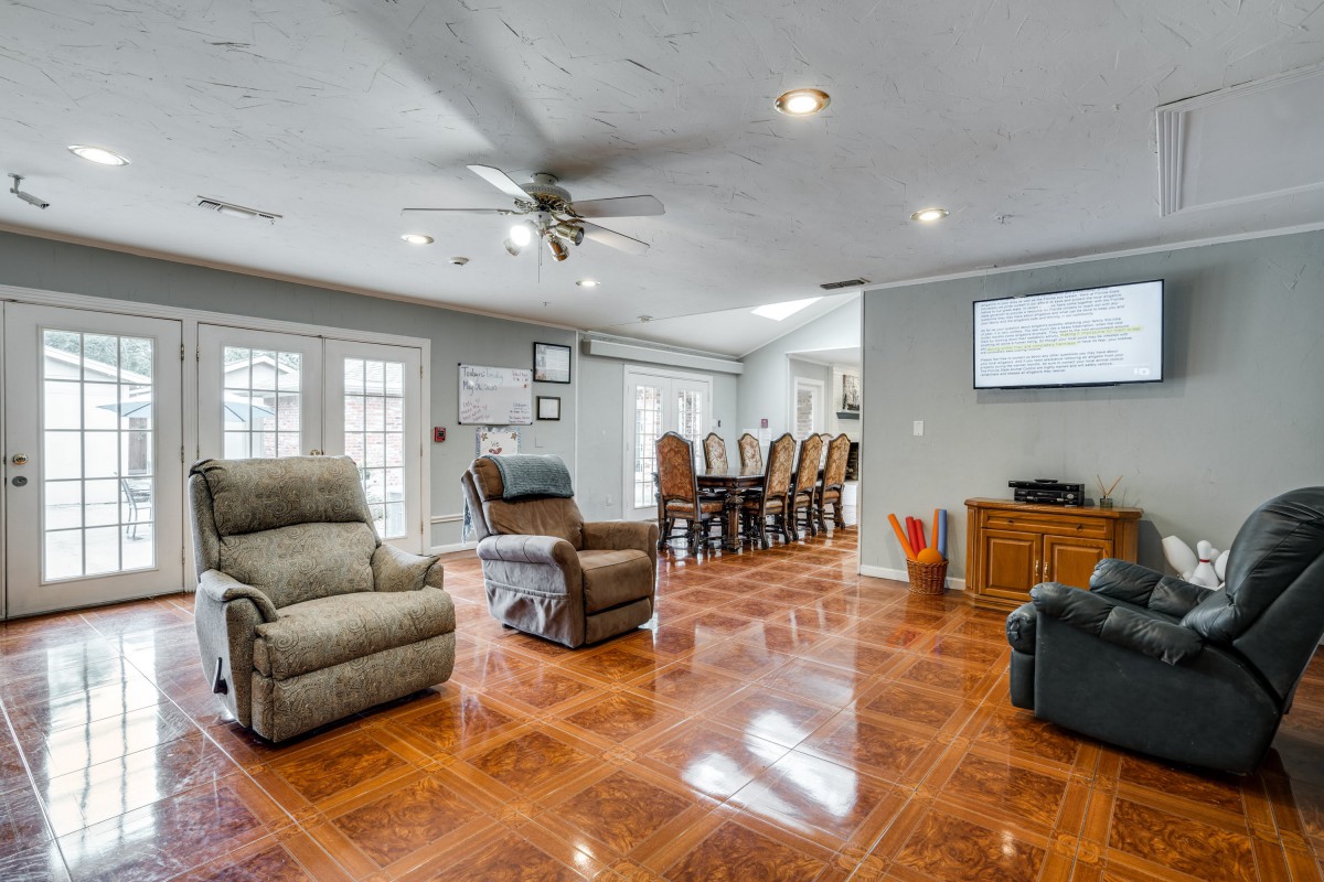 A spacious living room with hardwood flooring, featuring comfortable recliners and a dining area.