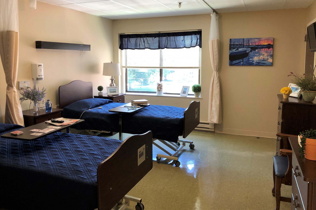 A clean, well-lit hospital room with two beds and a window.