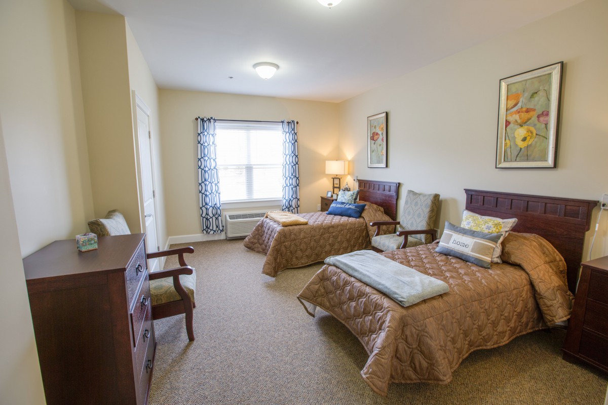 A cozy bedroom featuring two twin beds, a dresser, and comfortable seating.