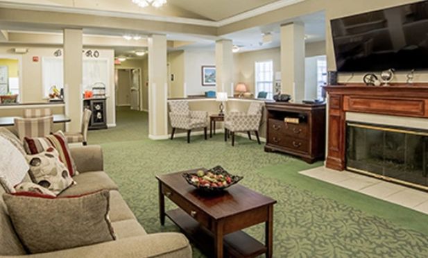 A cozy living room with comfortable seating and a television, featuring a carpeted floor and stylish decor.