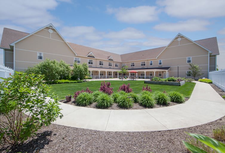 A residential building with a landscaped garden and pathway under a partly cloudy sky.