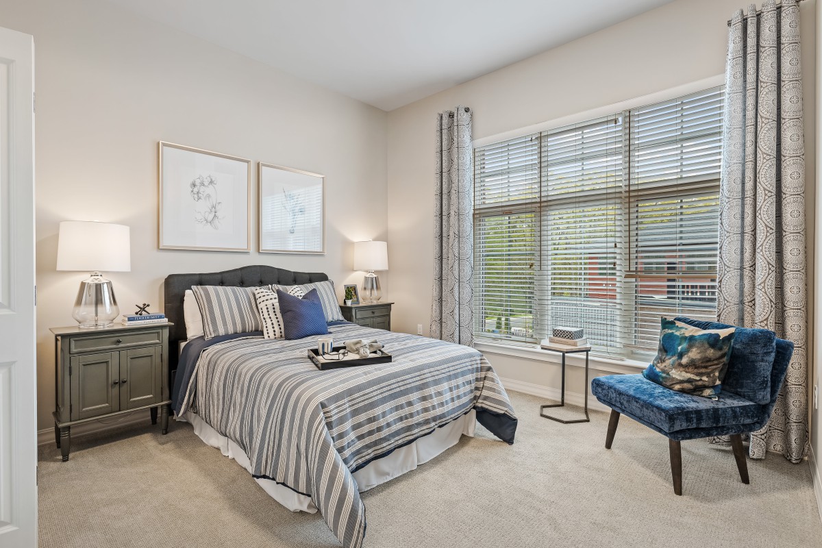 A cozy bedroom with striped bedding and large window light.