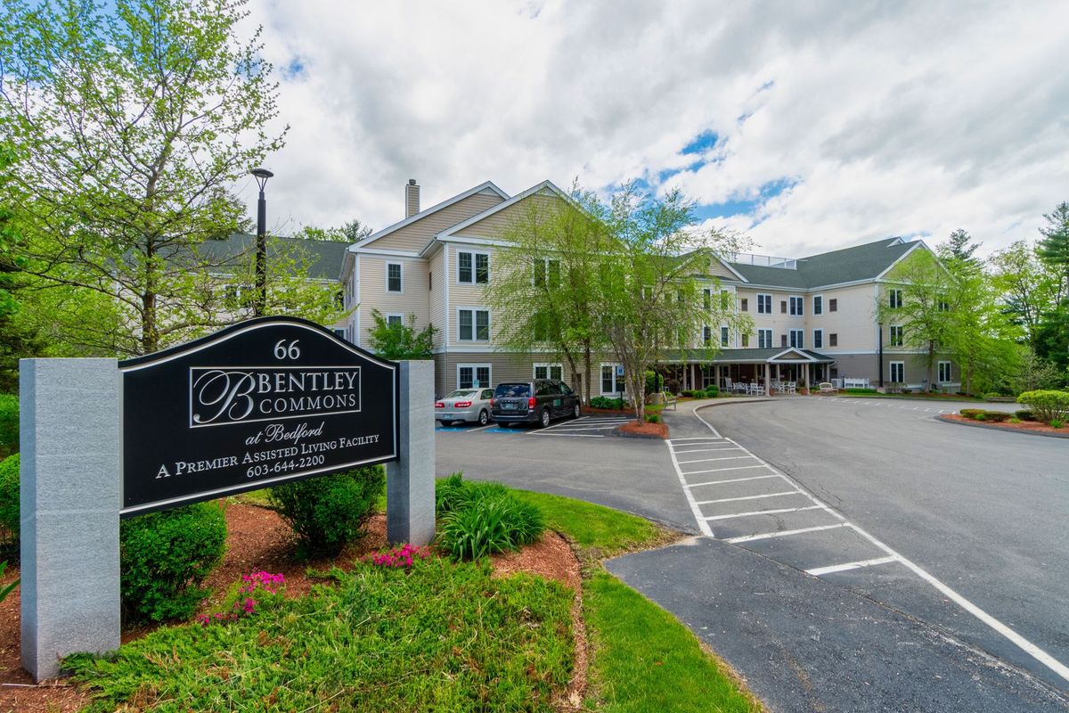 A hotel with a parking lot and surrounding greenery on a cloudy day.