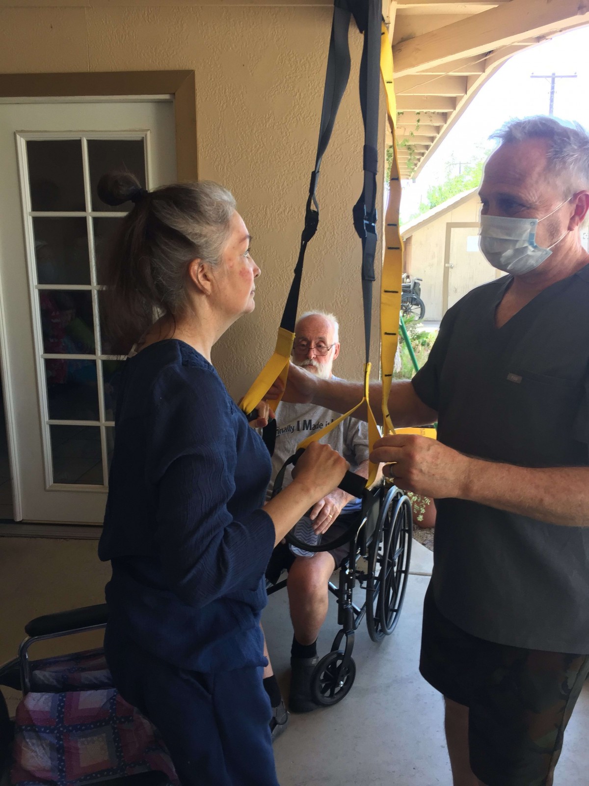 A caregiver assists a patient during a physical therapy session at home.