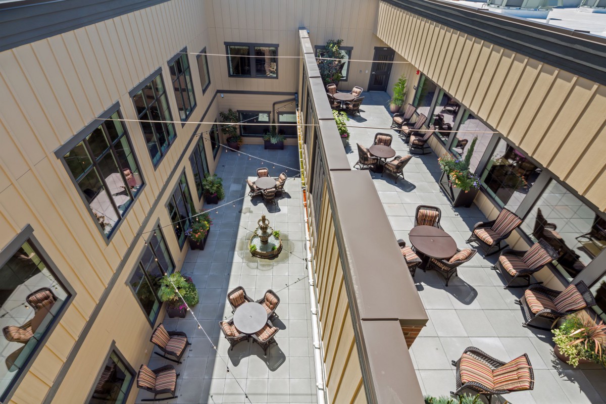 An aerial view of a courtyard with multiple tables and chairs arranged for outdoor seating.