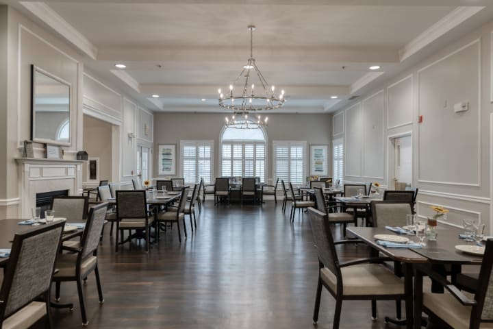 A spacious and elegantly designed dining room with chandeliers and arranged tables.