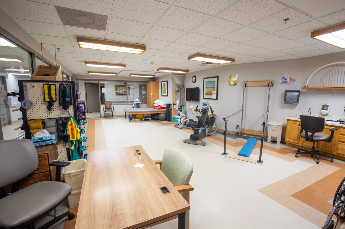 A well-equipped physical therapy room in a healthcare facility, featuring exercise equipment and therapy stations.