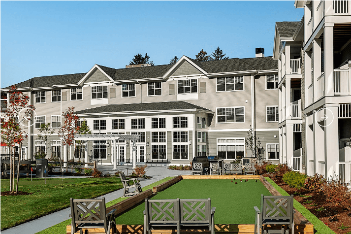 A modern residential building with a landscaped garden and seating area.