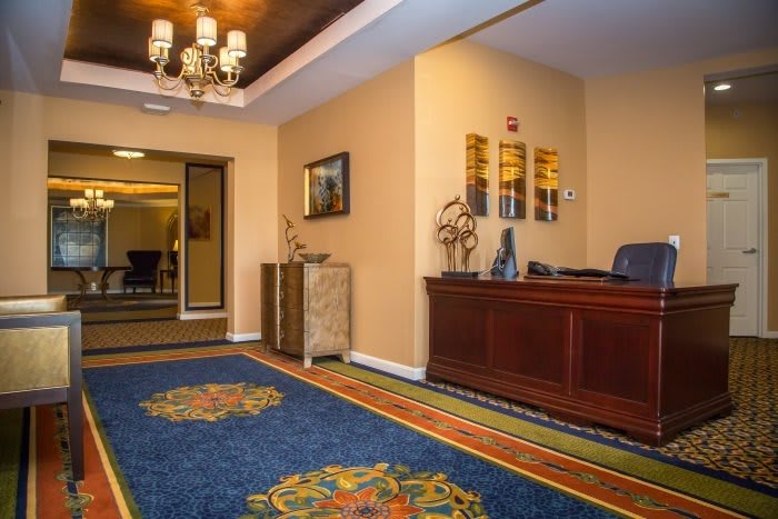 A warmly-lit reception area featuring a wooden desk, decorative carpets, and a chandelier.