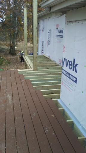 A view of an under-construction deck, showcasing wooden beams and flooring being installed.